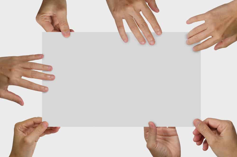Many hands holding a white blank poster